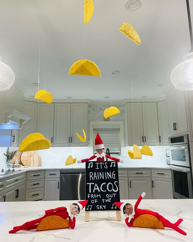 an elf is sitting in the kitchen with some tacos hanging from the ceiling above him