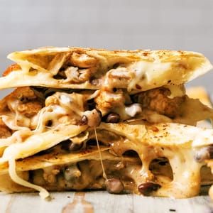 two quesadillas stacked on top of each other with meat and cheese toppings