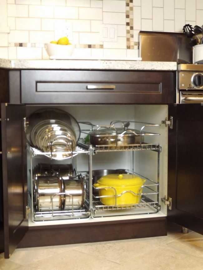 an open cabinet with pots and pans on the bottom shelf, in a kitchen