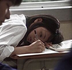 a woman laying on top of a desk writing