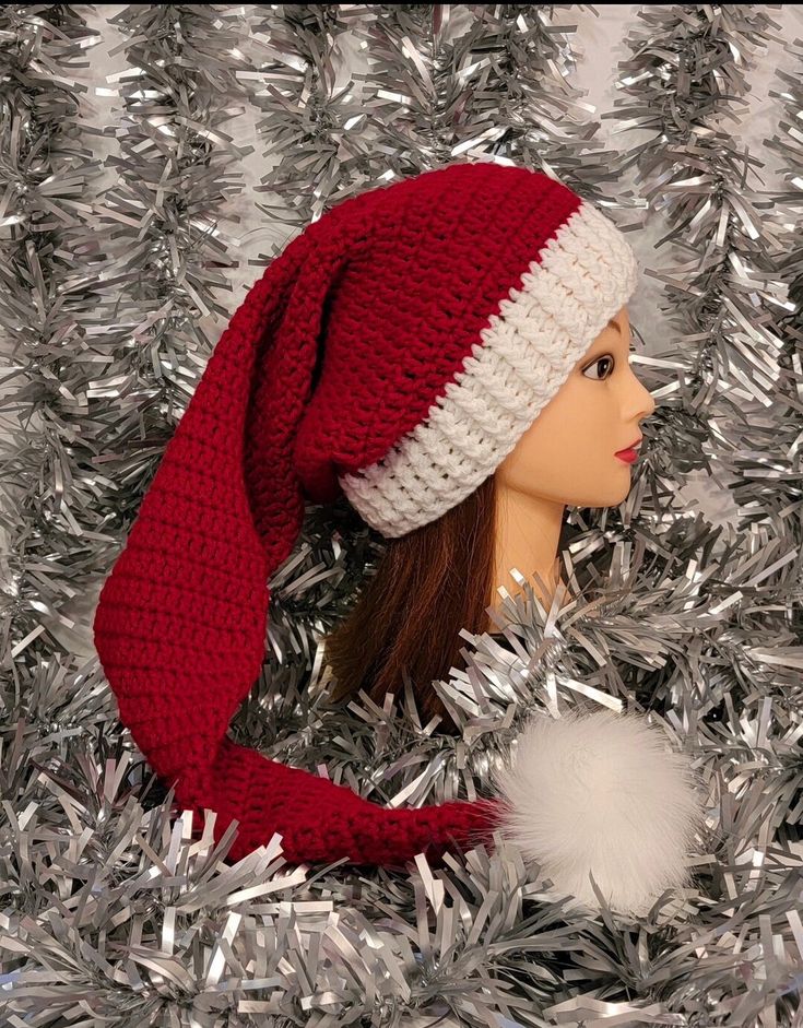 a mannequin head wearing a red and white knitted hat on top of tinsel