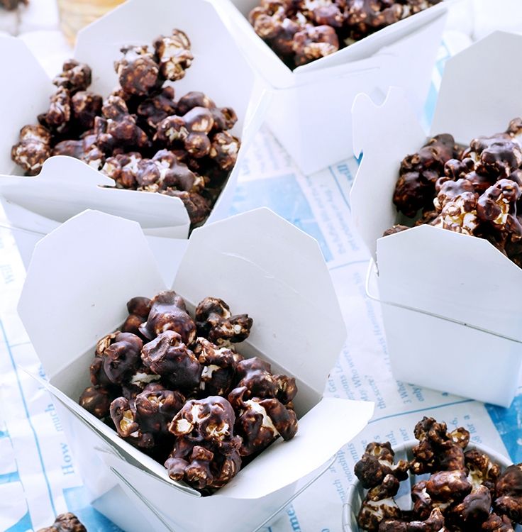 four white boxes filled with chocolate covered candies on top of a blue and white table cloth