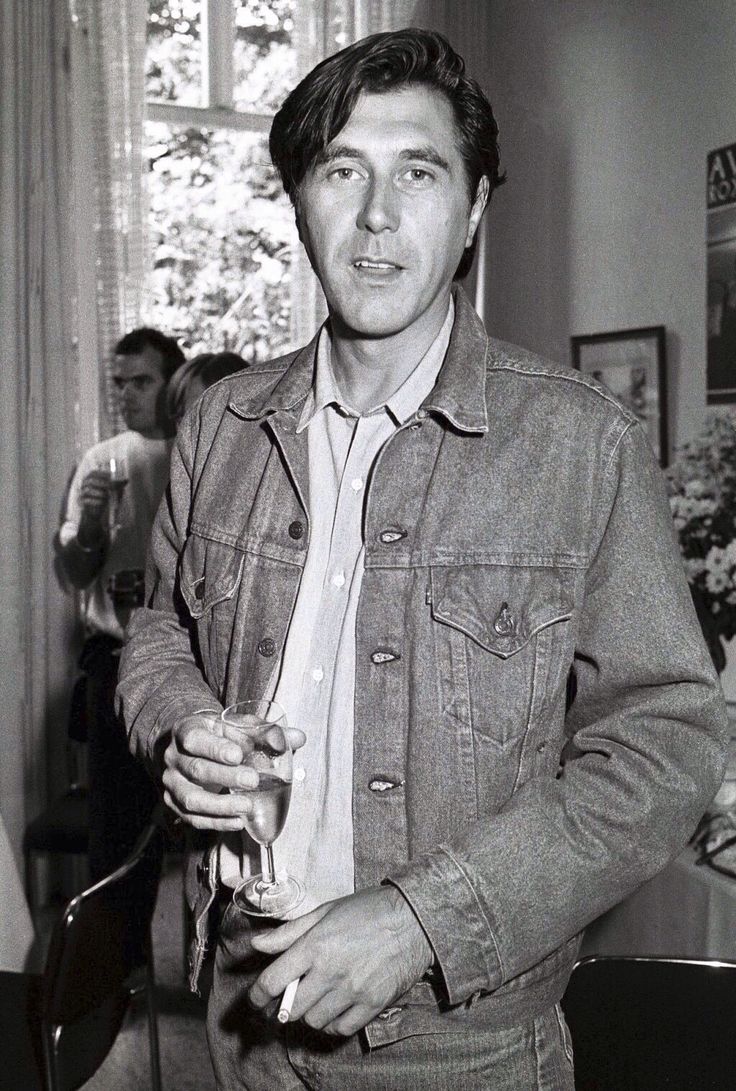 a black and white photo of a man holding a drink