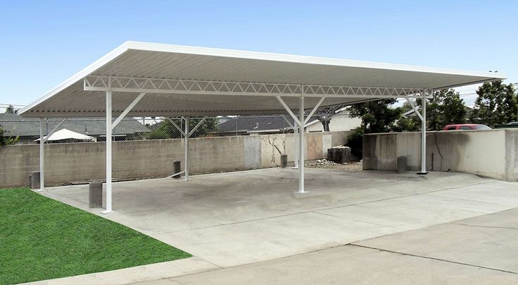 an outdoor covered parking lot with grass in the foreground and a car parked on the other side