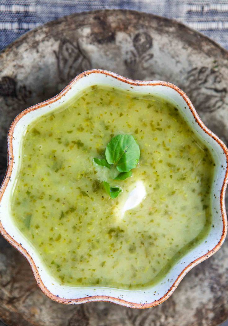 a bowl filled with green soup on top of a plate