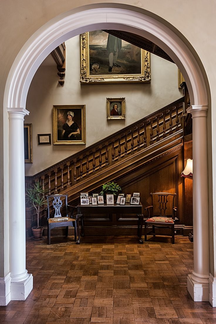 an archway leading up to a living room with pictures on the wall and wooden floors