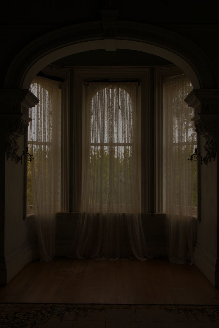 an empty room with sheer curtains on the windows