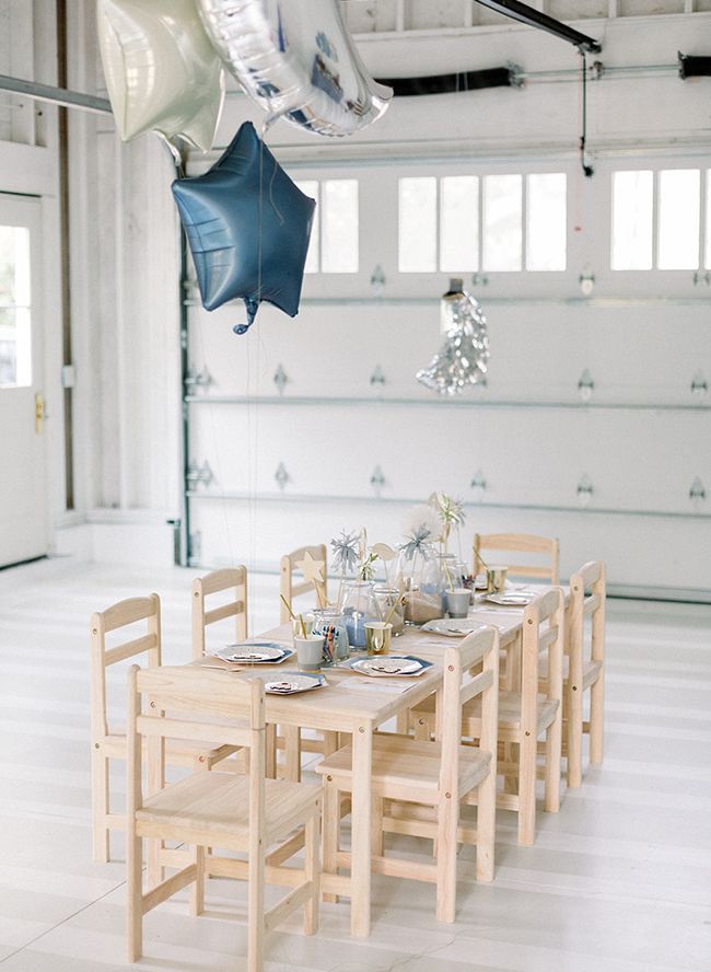 a dining table and chairs in a room with white tile flooring, hanging decorations