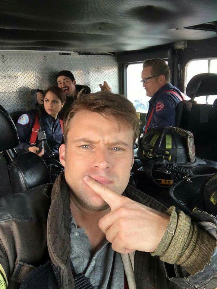 a man is sitting in the back of a fire truck and pointing to his finger