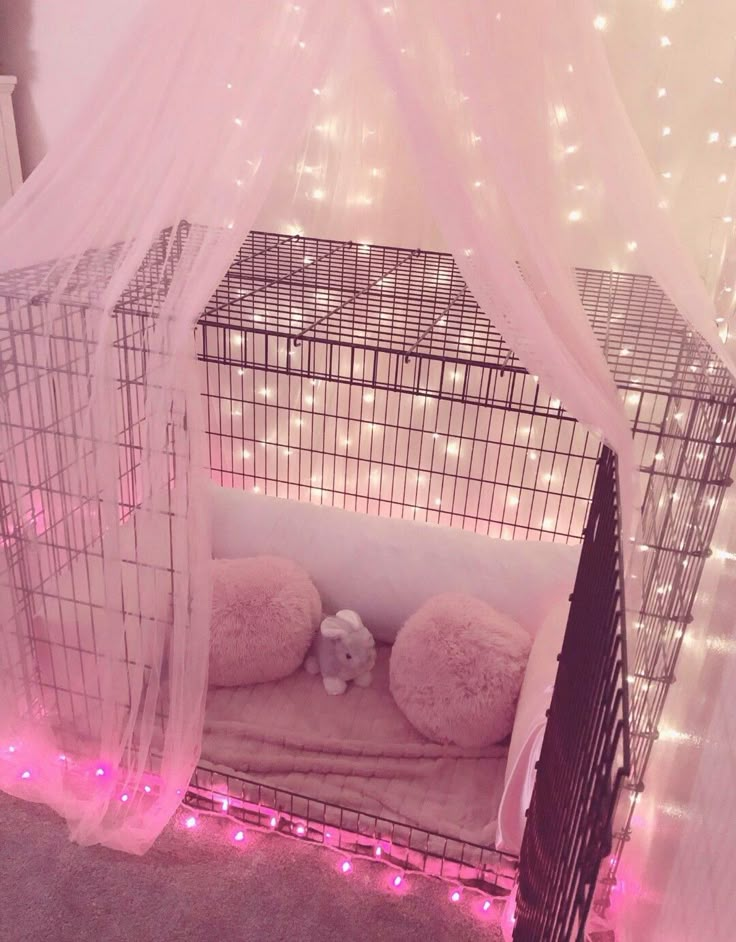 a dog cage with lights around it and a teddy bear in the bed on top