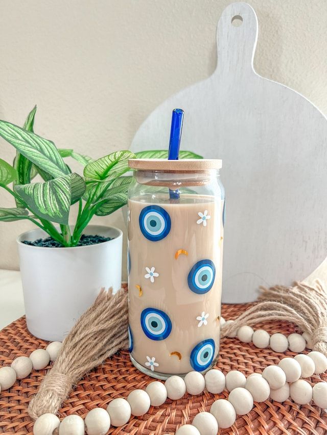 a glass with a blue lid sitting on top of a table next to a potted plant