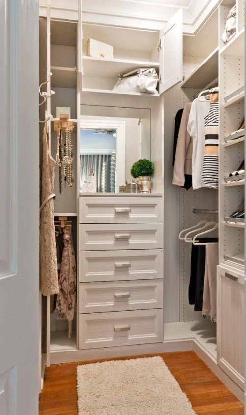 an organized closet with white drawers and shelves