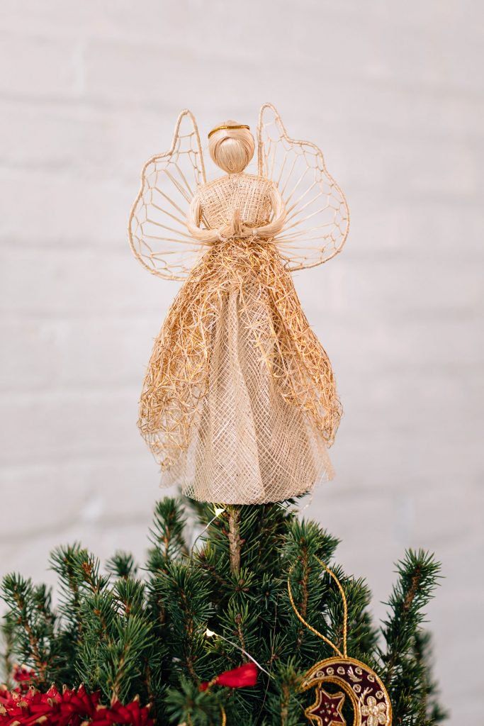 an angel figurine sitting on top of a christmas tree