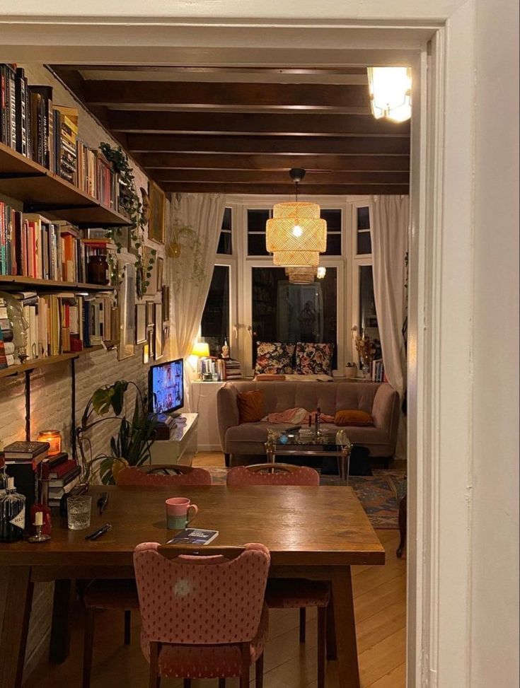 a living room filled with furniture and a wooden table in front of a book shelf