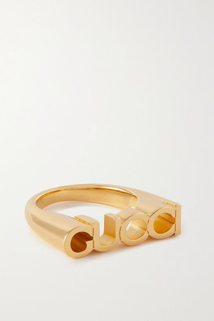 This ring is an easy way to show your love for all things Gucci. Made from gold-tone metal, it's cast in the shape of the label's logo and has a chunky shape. Luxury Gold-tone Jewelry With Logo, Luxury Gold-tone Logo Jewelry, Luxury Gold-tone Jewelry With Logo Lettering, Designer Gold Jewelry With Metal Logo, Designer Yellow Gold Jewelry With Logo Lettering, Designer Gold Jewelry With Logo, Classic Gold Jewelry With Logo, Modern Metal Jewelry With Logo, Classic Yellow Gold Jewelry With Logo