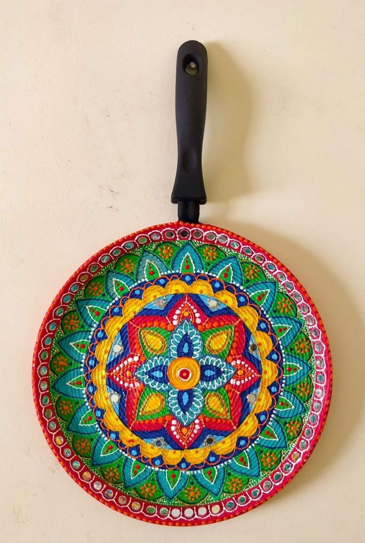 a colorful plate with a black handle hanging on the wall