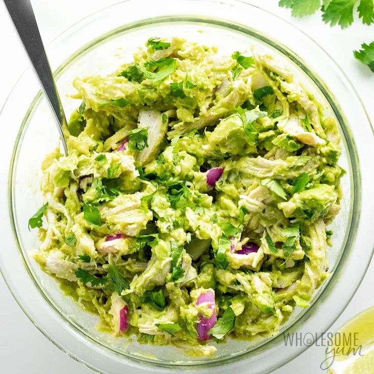 a glass bowl filled with guacamole and cilantro