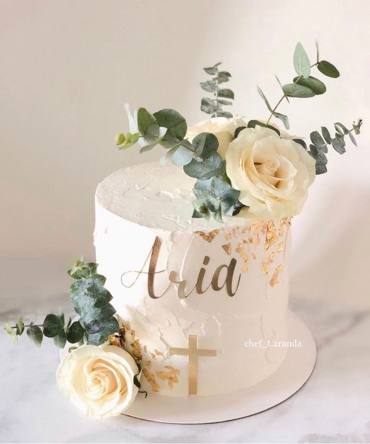 a white cake with flowers and greenery on top is sitting on a marble table