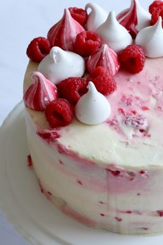 a cake with raspberries and white frosting