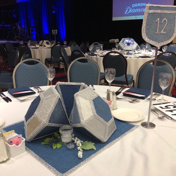 the table is set up for a formal function with blue linens and silver decorations