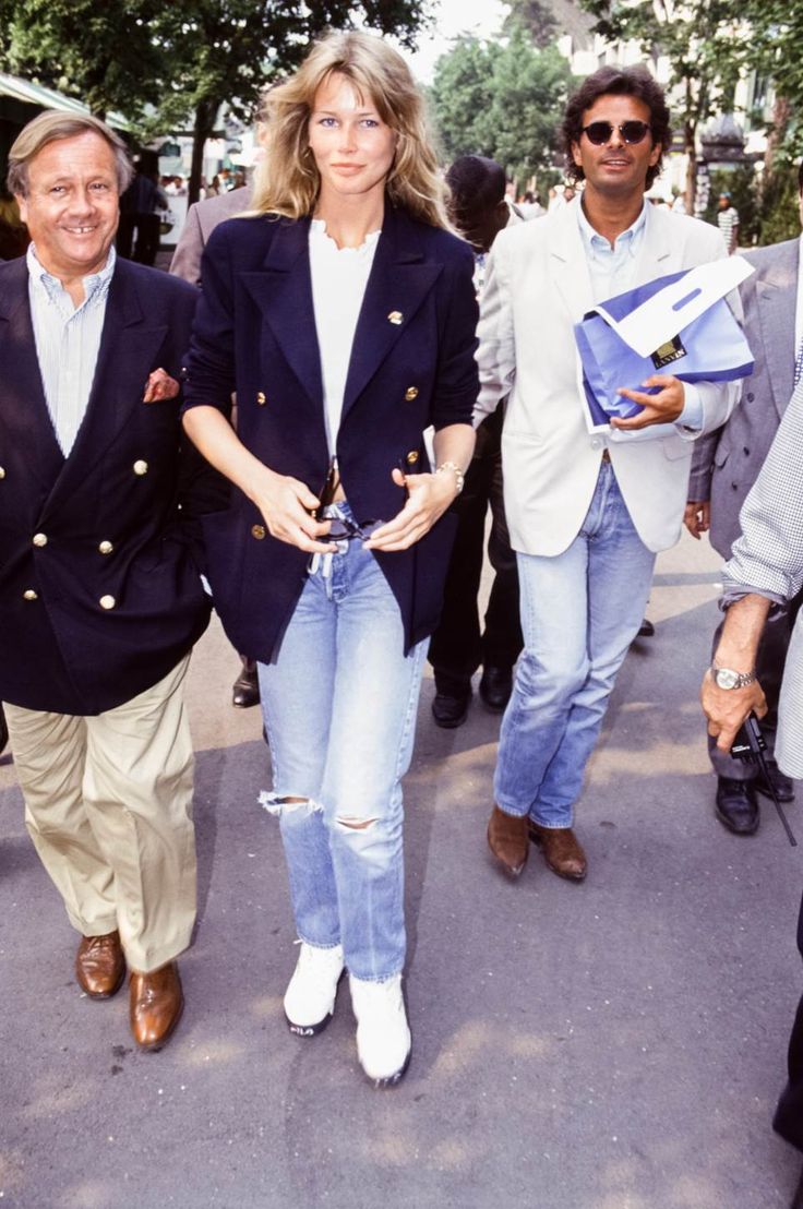 two men and a woman are walking down the street in front of some other people