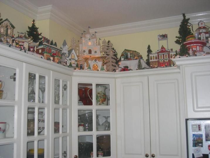 a kitchen filled with lots of white cupboards covered in christmas decorations on top of them