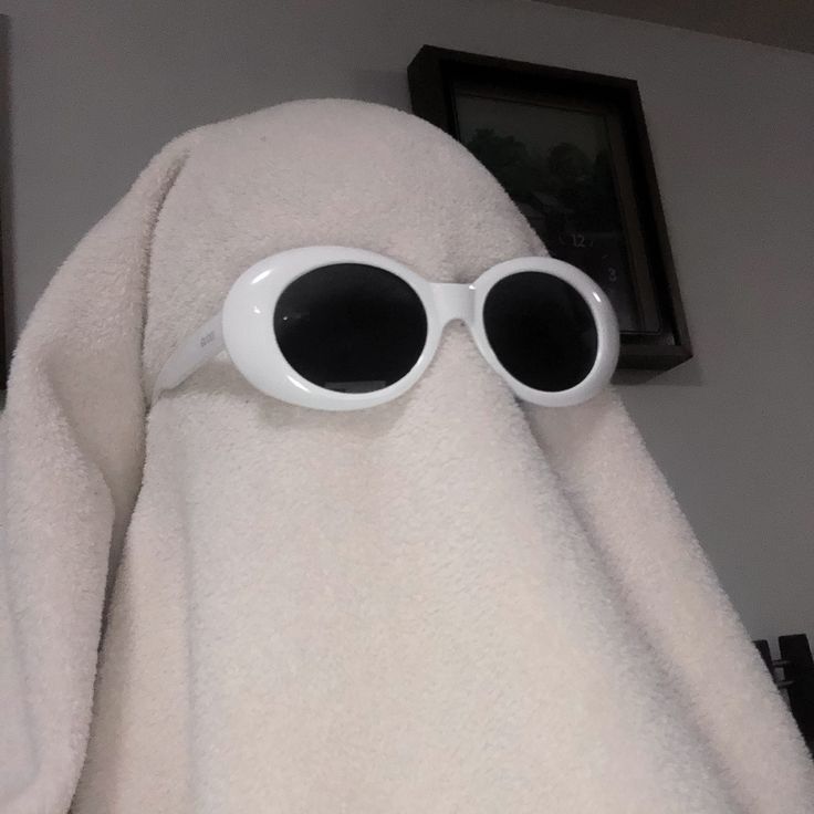 a white towel with sunglasses on it and a black framed picture above the eyes that is hanging from the wall