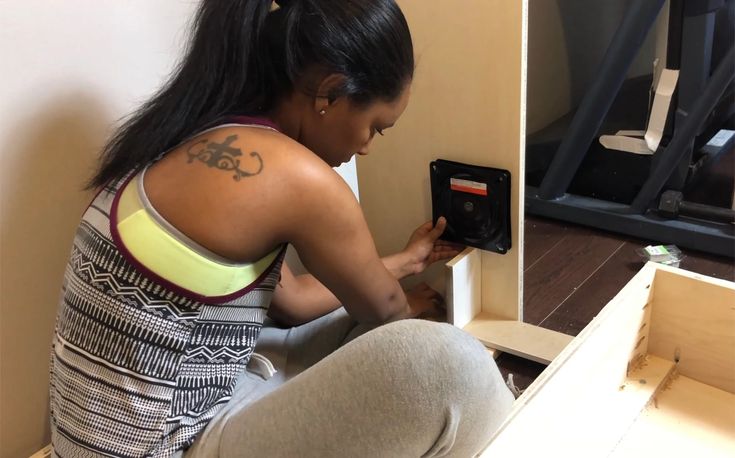 a woman squatting on the floor looking at an electronic device