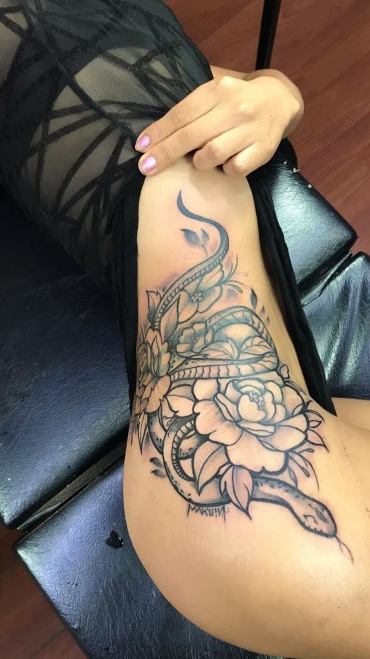 a woman with a tattoo on her arm and leg is sitting in a black chair