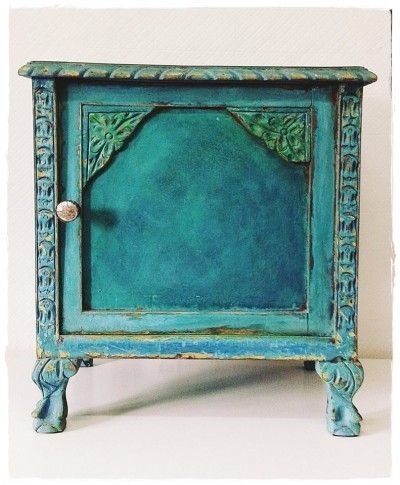 an old blue cabinet with ornate carvings on the front and sides, painted teal green