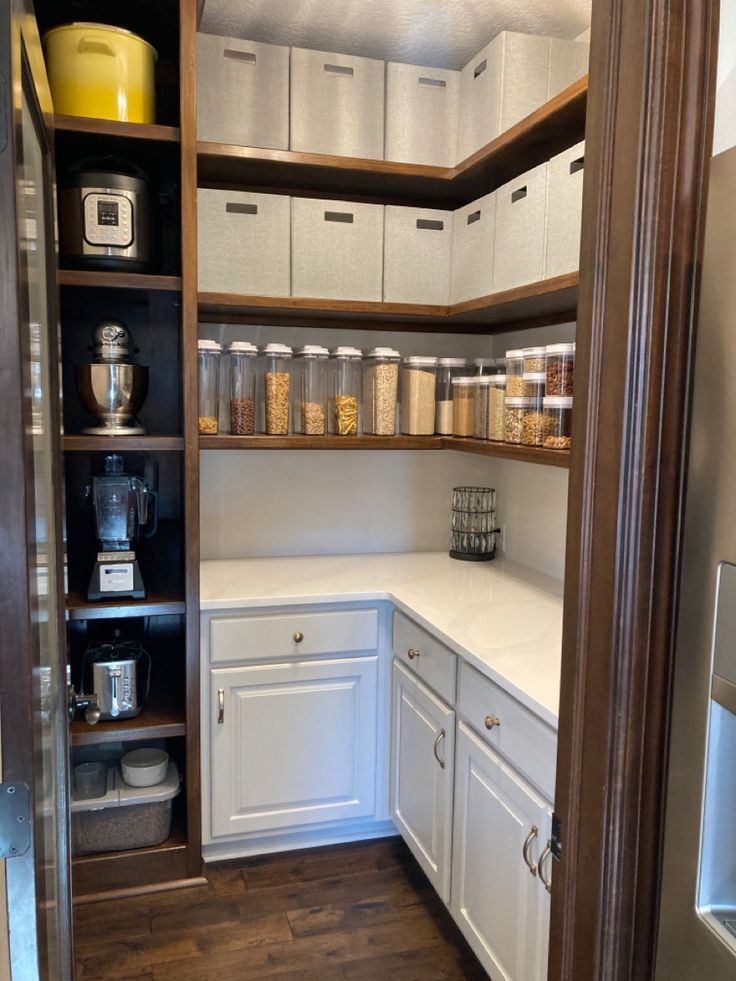 a kitchen with white cabinets and lots of drawers in the pantry area that is open