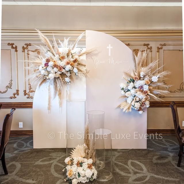 two tall floral arrangements on display in front of a wall