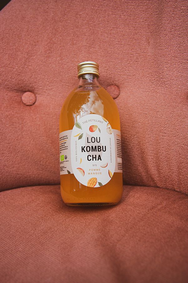 a bottle of kombu cha sitting on the arm of a pink chair with buttons