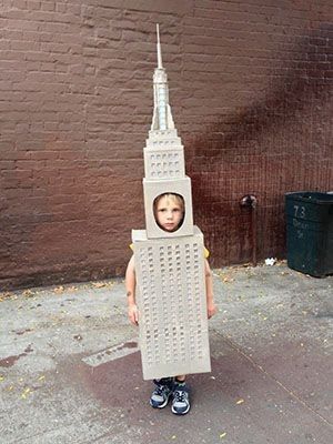 a young boy standing in front of a building with a cardboard cut out of it's face