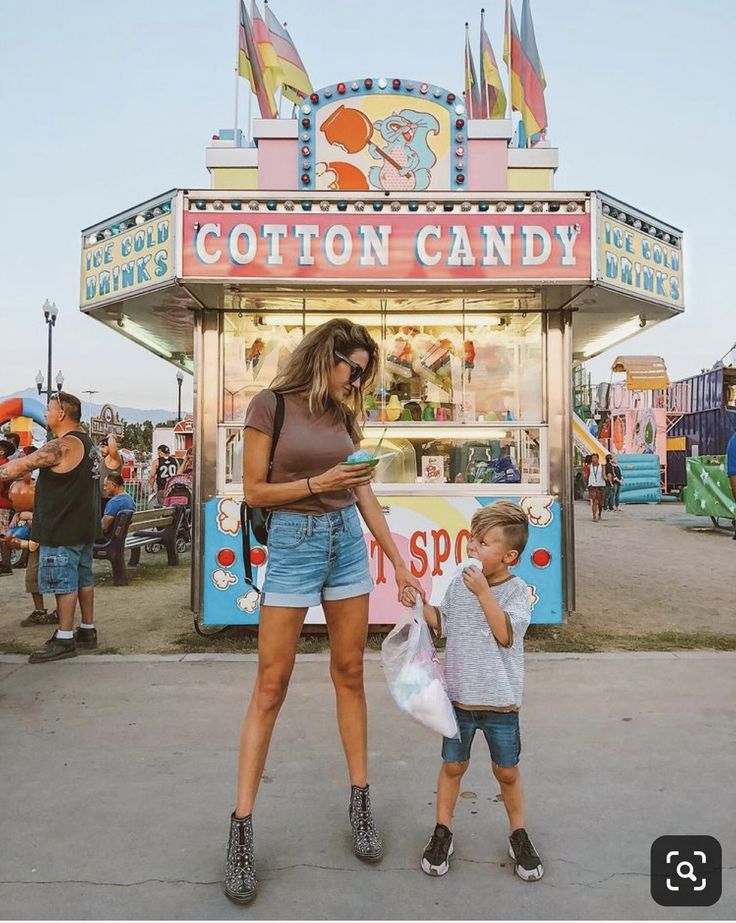 a woman and child standing in front of a carnival