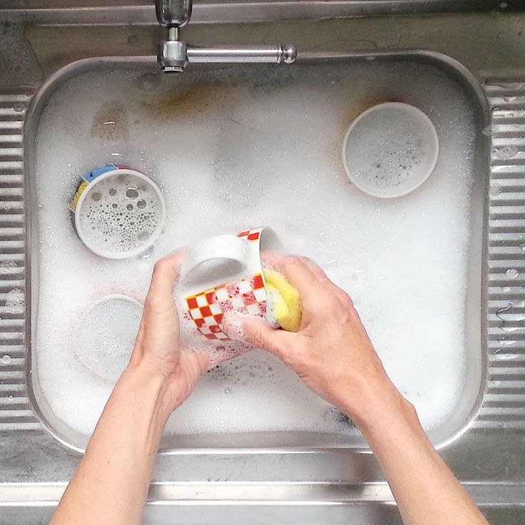 a person is washing dishes in a sink with soap and water on the rims