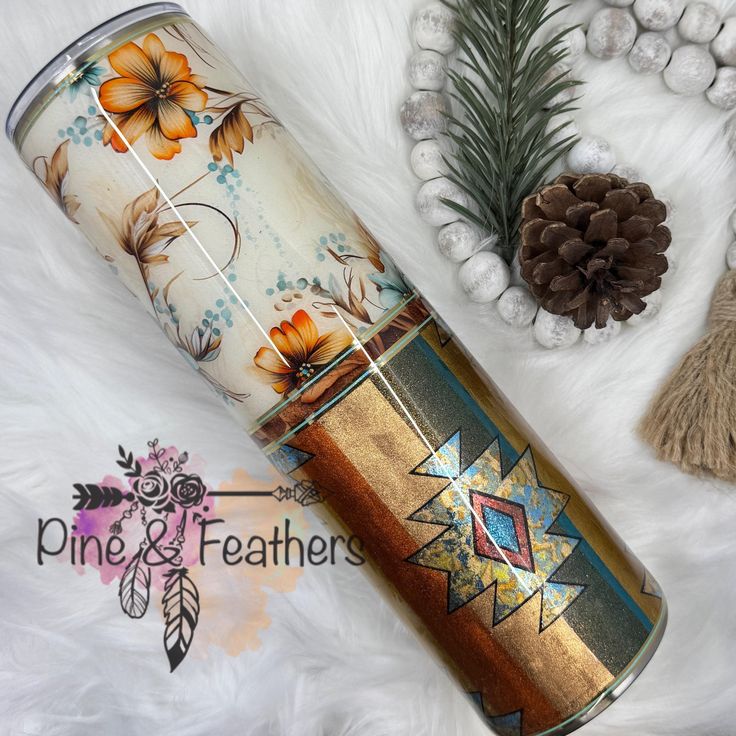 the tumbler is decorated with flowers and leaves on it, along with pine cones