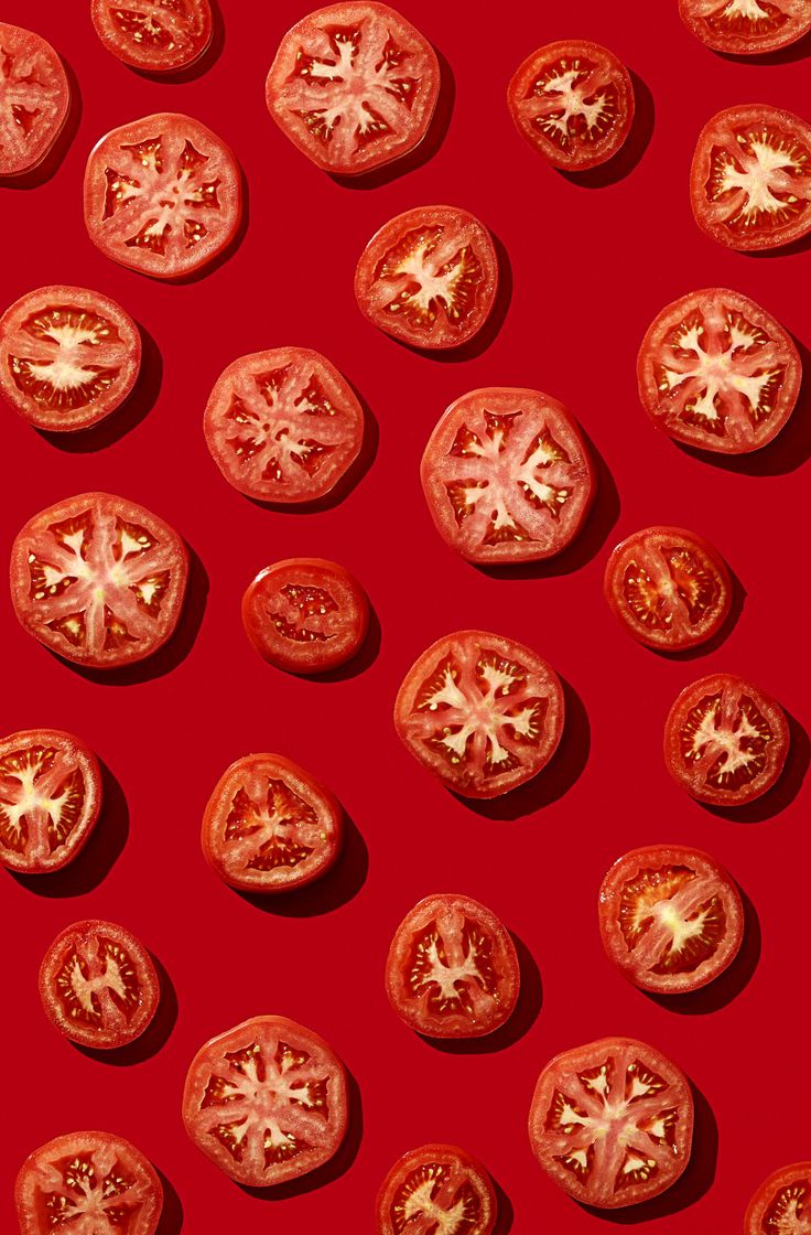 tomatoes are arranged on a red surface with white stars in the middle, and one tomato has been cut into smaller pieces