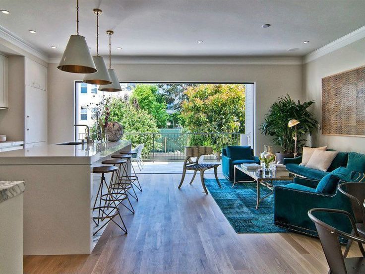 a living room filled with furniture next to a kitchen and an open door leading to a balcony