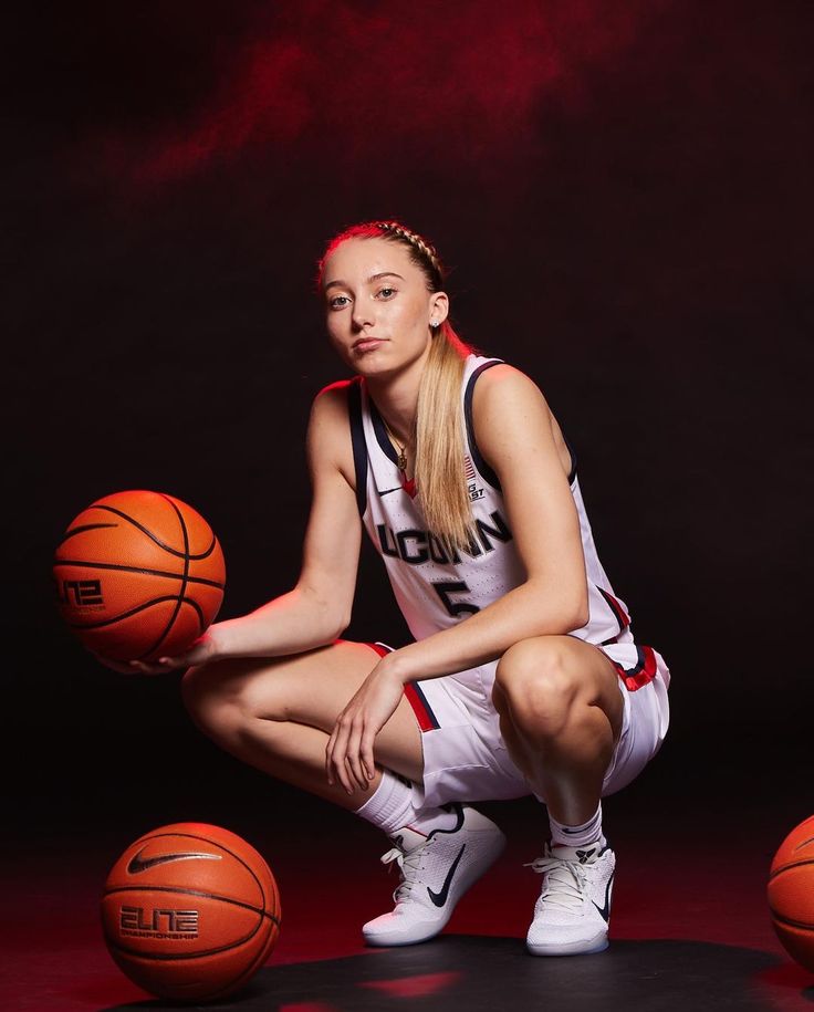 a female basketball player sitting on the floor next to three balls in front of her