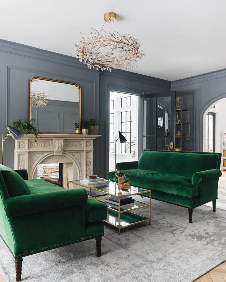 a living room filled with green couches and chairs next to a fire place in front of a fireplace