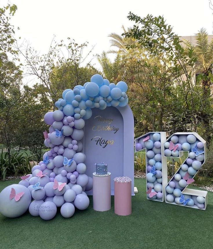 an outdoor area with balloons and decorations for a birthday party in the shape of letters