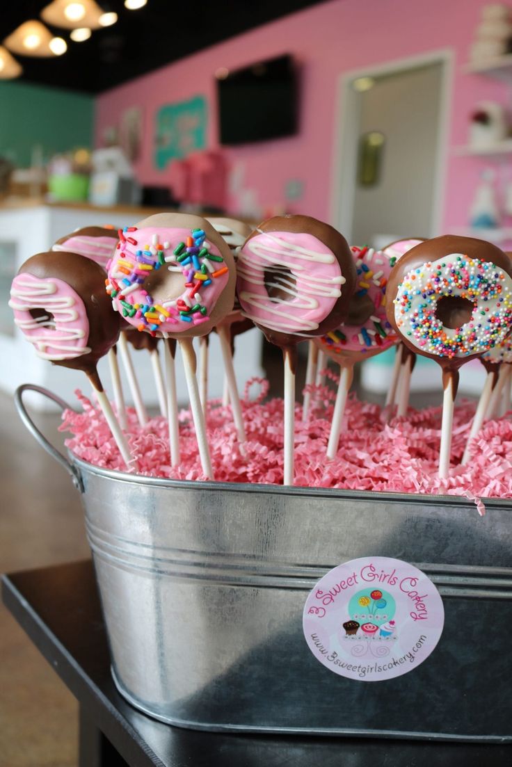 there are many donuts with sprinkles on them in the bucket and pink frosting