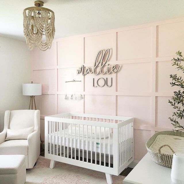 a baby's room with pink walls and white crib, chandelier hanging from the ceiling