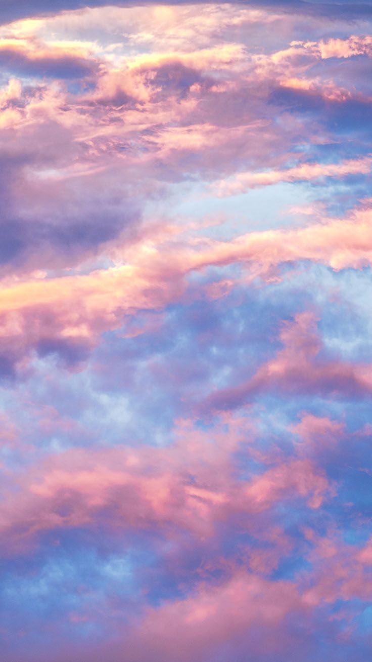 an airplane is flying in the sky with pink and blue clouds behind it at sunset