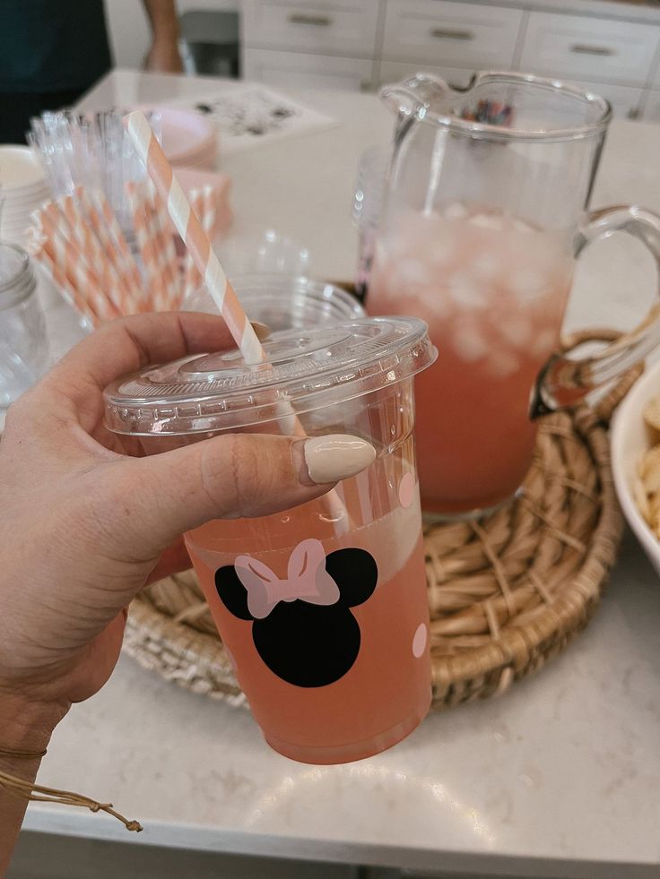 a person holding a cup with straws in it and minnie mouse on the lid