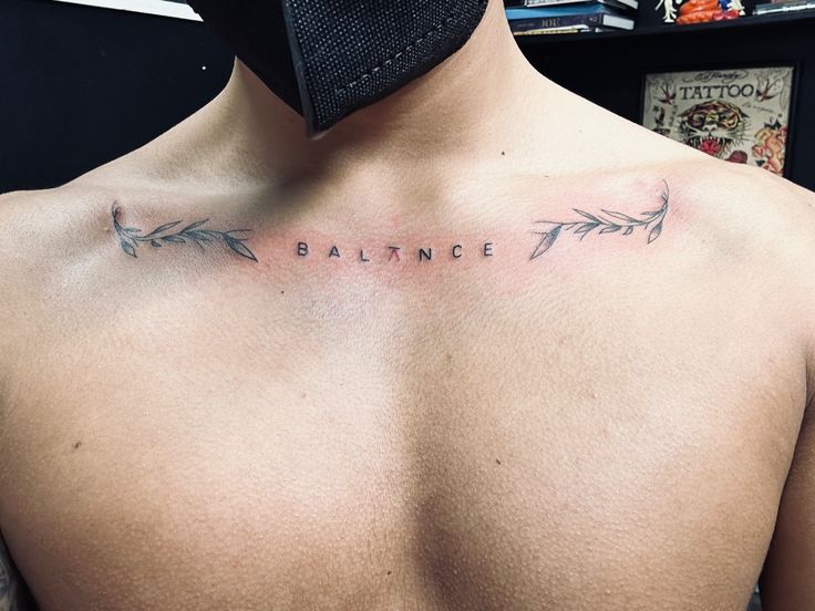 a man's chest with an arrow tattoo on his left side and the word balance written in cursive font