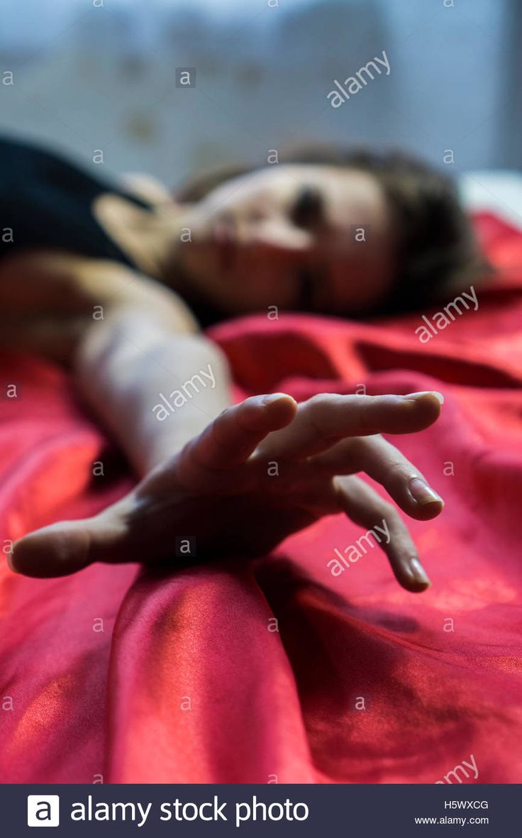 a woman laying in bed with her hand extended out to the side - stock image