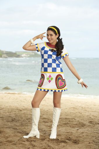 a woman in a costume standing on the beach with her arms out and legs crossed