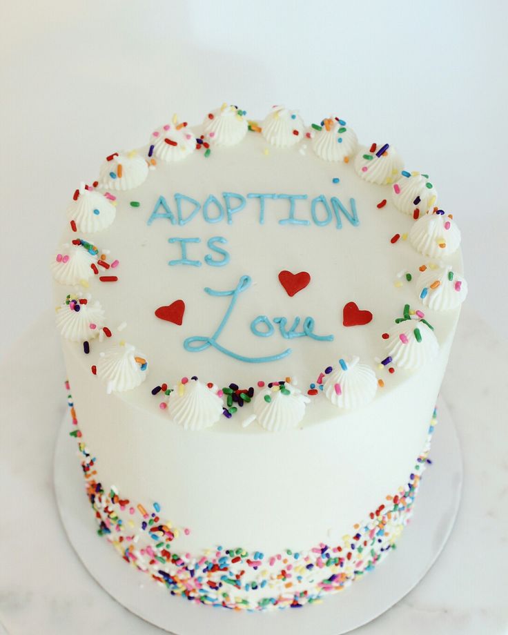 a white cake with confetti and sprinkles on it that says adoption is love